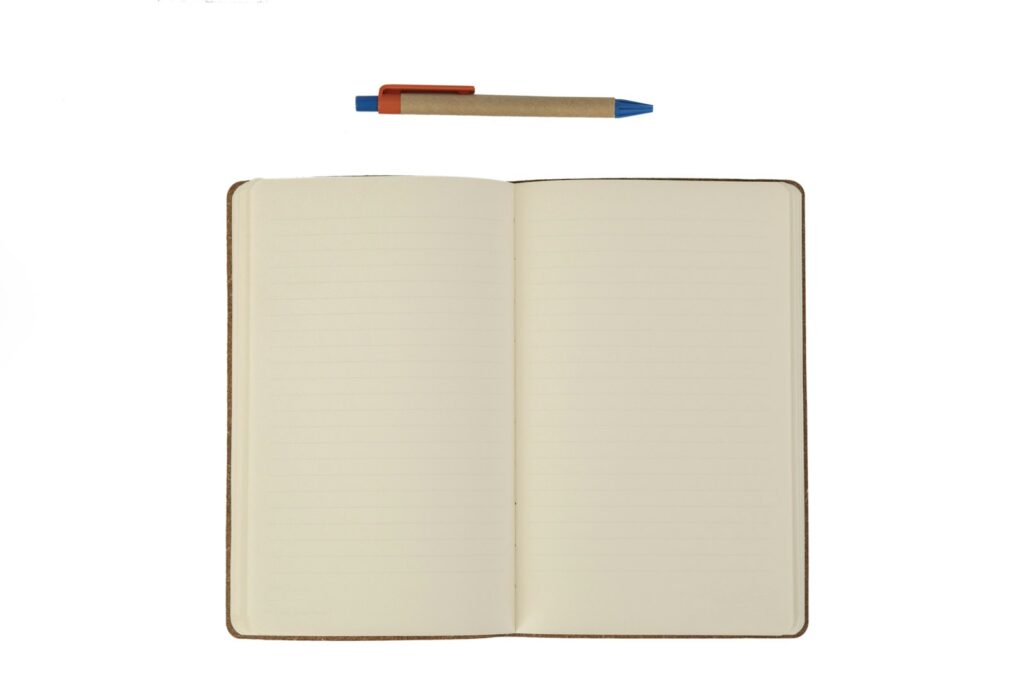 Open lined notebook with blank pages and a pen on a white background.
